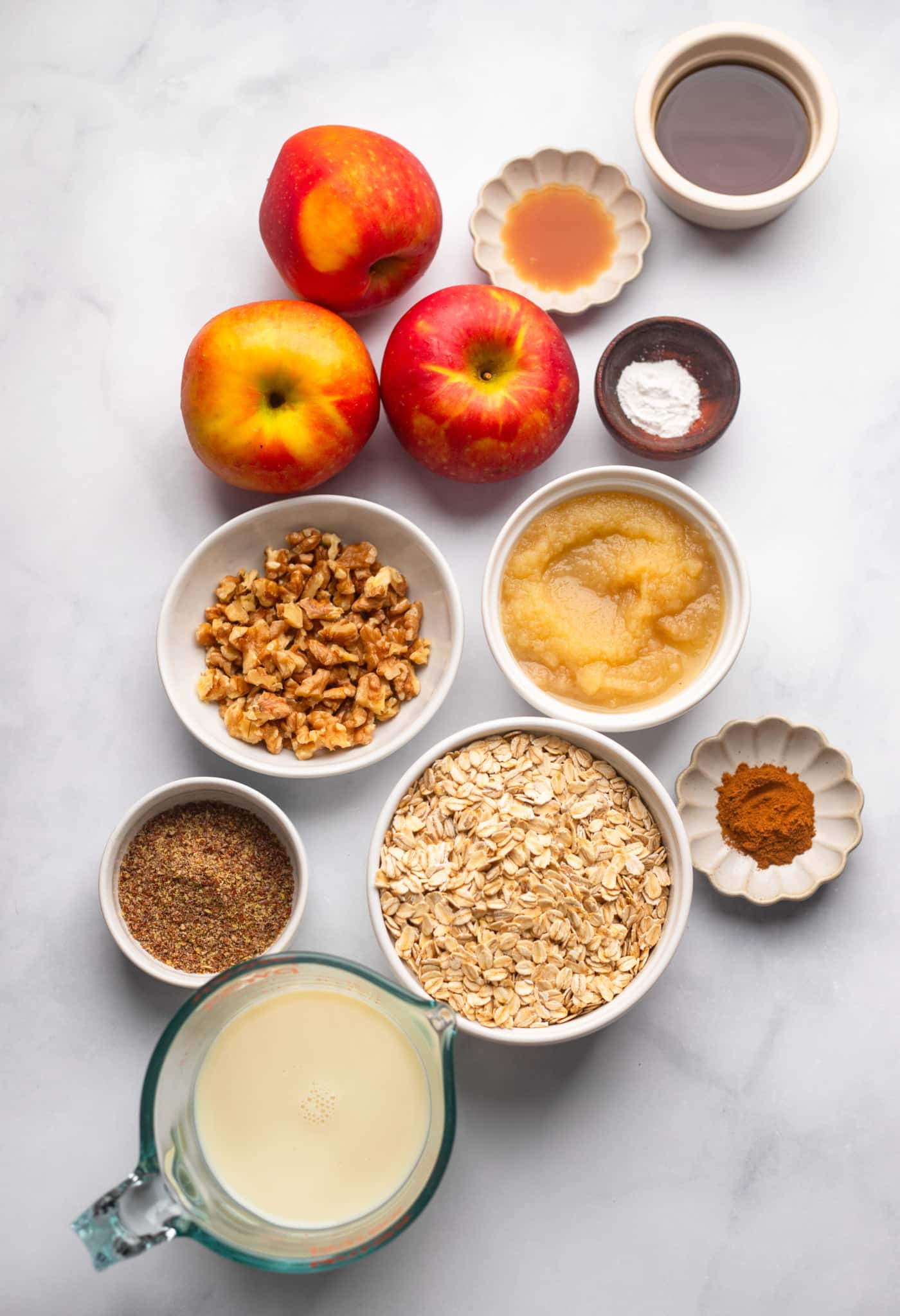 Ingredientes para aveia assada em maçã em tigelas brancas individuais.