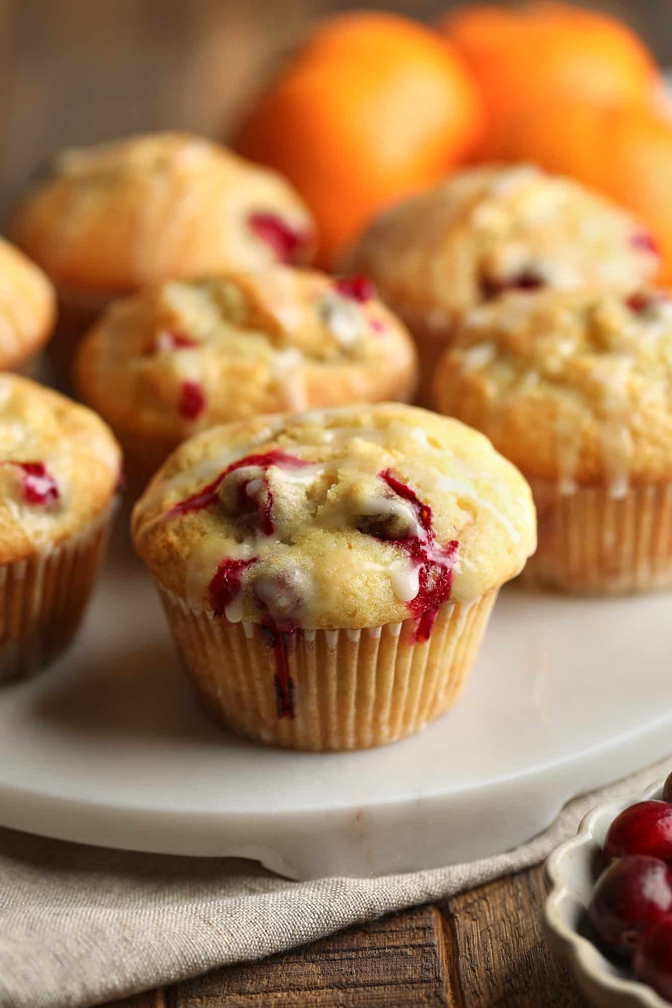 Feche em um muffin de laranja de cranberry envidraçado em um prato branco.