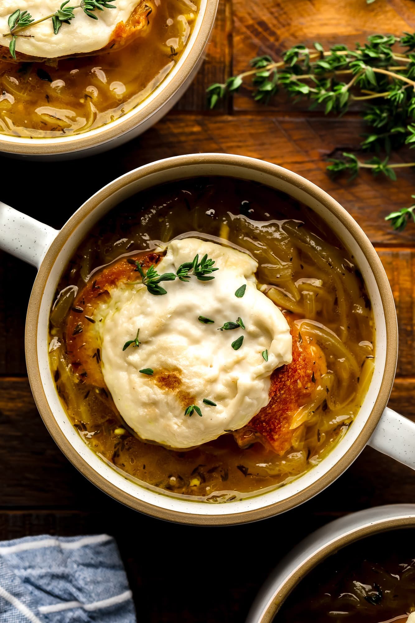 Uma tigela de sopa de cebola francesa vegana coberta com pão de queijo vegano torrado.
