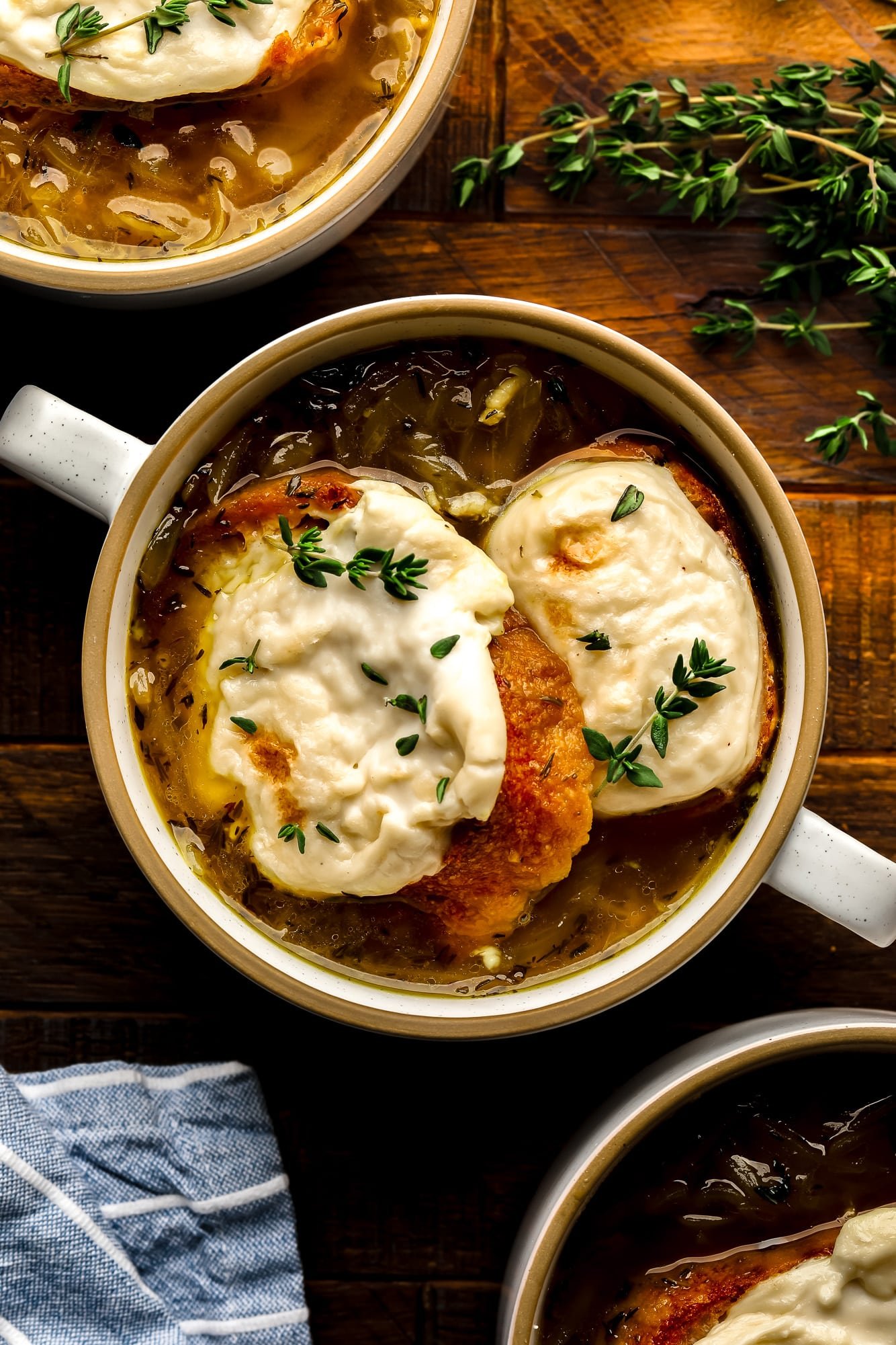 Uma tigela de sopa de cebola francesa vegana coberta com pão de queijo vegano torrado.