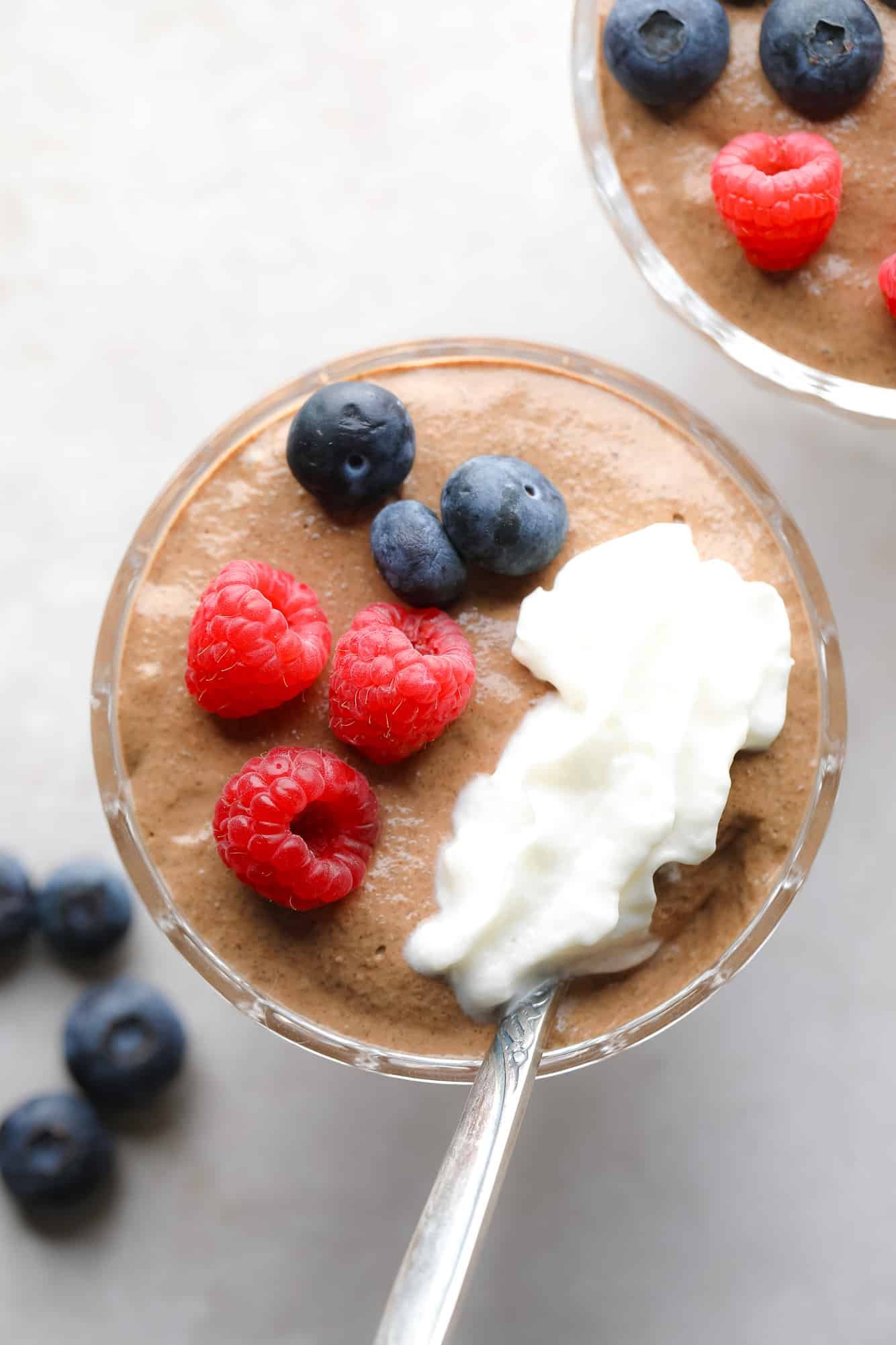 Feche em um pote de pudim de chia de chocolate coberto com frutas e chantilly.