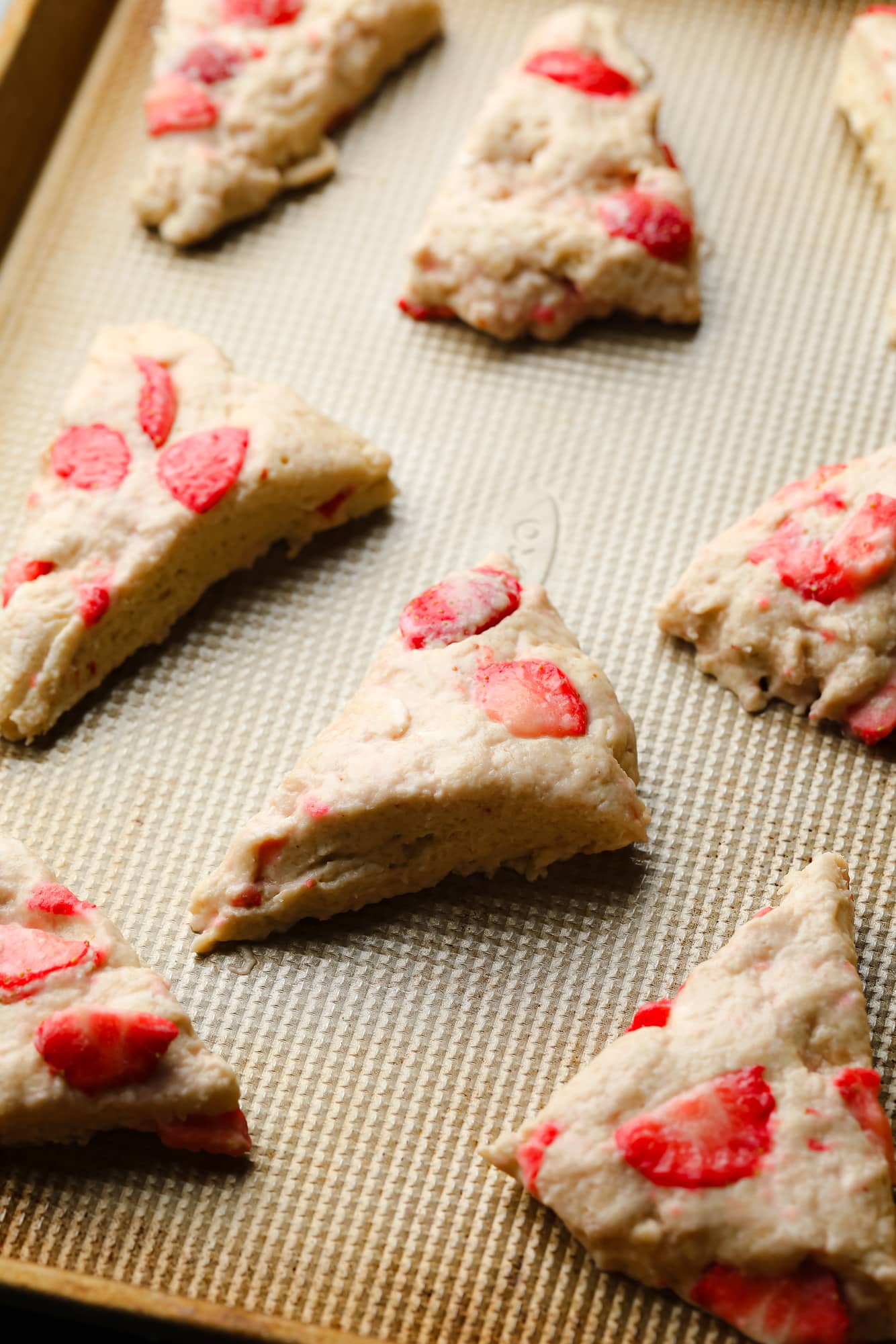 Scones de morango vegano não cozidos em uma assadeira.