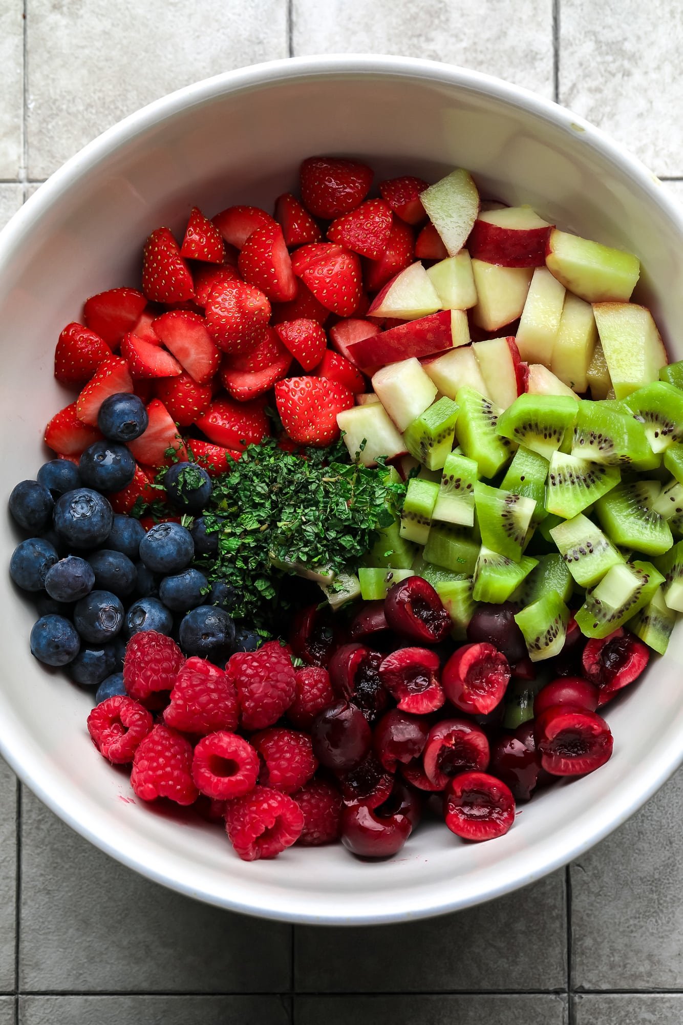 Os ingredientes para uma salada de frutas em uma tigela branca grande.